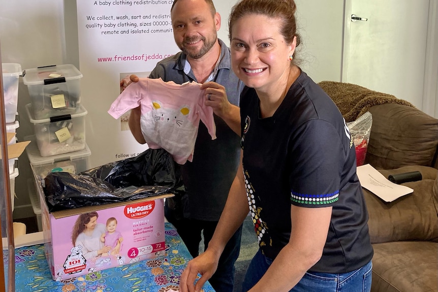 Dee and Weylon Malek stand over a table folding baby clothes into a box