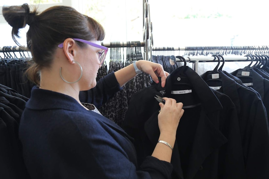 A woman checking a coat on a rack.