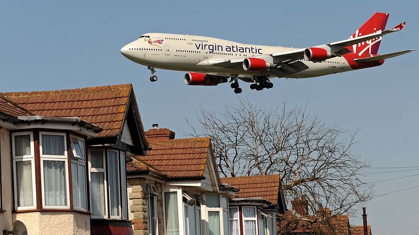 A Virgin Atlantic passenger jet flies over houses as it prepares to land at Heathrow Airport