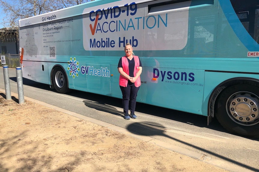 Nurse standing in front of a bus being used as a COVID-19 vaccination mobile hub.