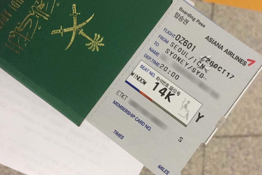 A boarding pass and passport held by a Saudi Arabian woman.