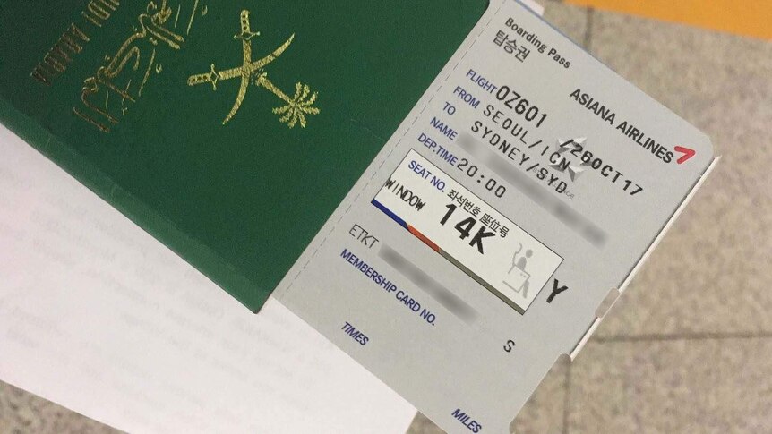 A boarding pass and passport held by a Saudi Arabian woman.