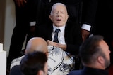 Jimmy Carter in a wheel chair with a blanket over his lap. 