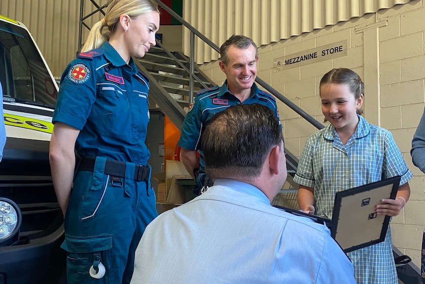 a young girl receives a certificate from a paramedic
