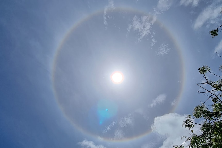 A blue sky with minimal clouds and a halo around the sun.
