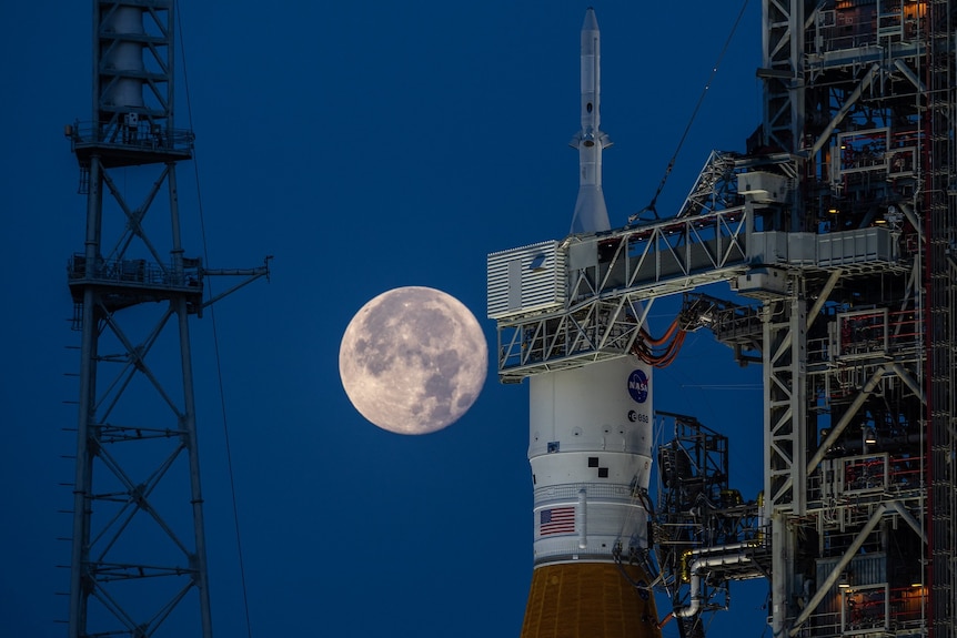 The strawberry supermoon rises behind NASA's Artemis 1 moon rocket