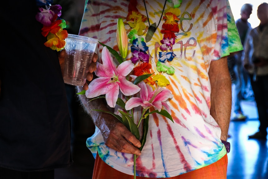 Man in tie dye shirt holding flowers