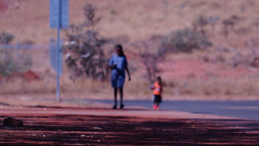 A woman and child walk down a street in the WA Pilbara town of Roebourne.