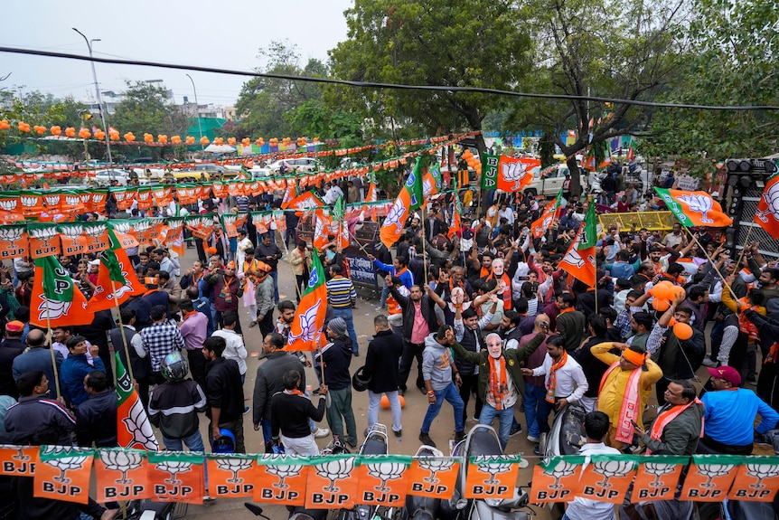 Bharatiya Janata Party campaigners crowd together with the party's signs and flags on display.