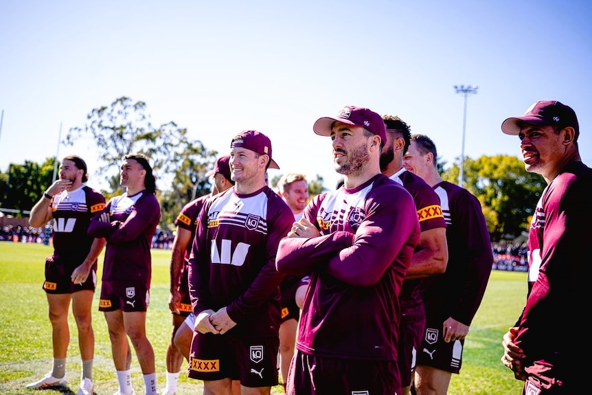 A group of footballers in Maroon training gear standing together.