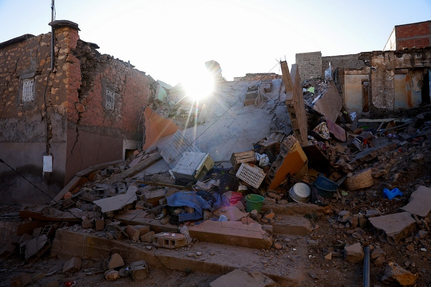 The sun rises over a large pile of rubble.