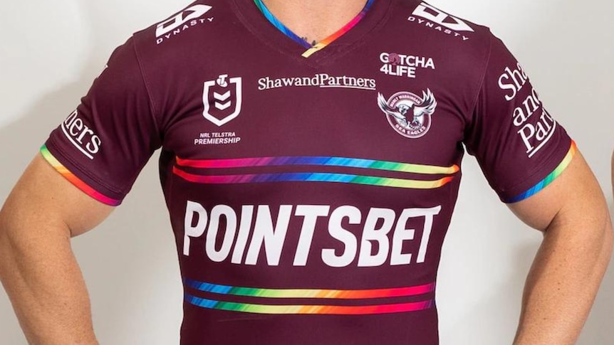Man wearing the Manly Eagles pride jersey with small rainbow stripes.