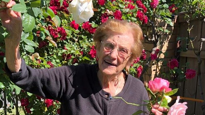 Luisa Staffieri smiles as she holds a bunch of roses in a backyard garden.