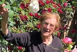 Luisa Staffieri smiles as she holds a bunch of roses in a backyard garden.