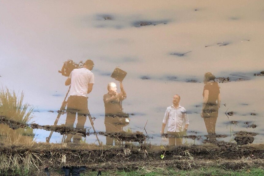 Reflection of Four Corners team and equipment in muddy pond.