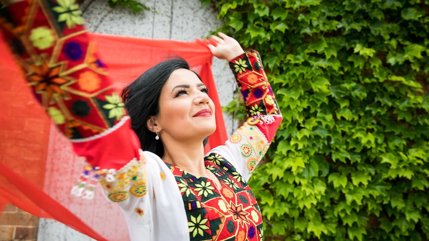 Maryam Zahid dressed in red, swirling a scarf behind her head.