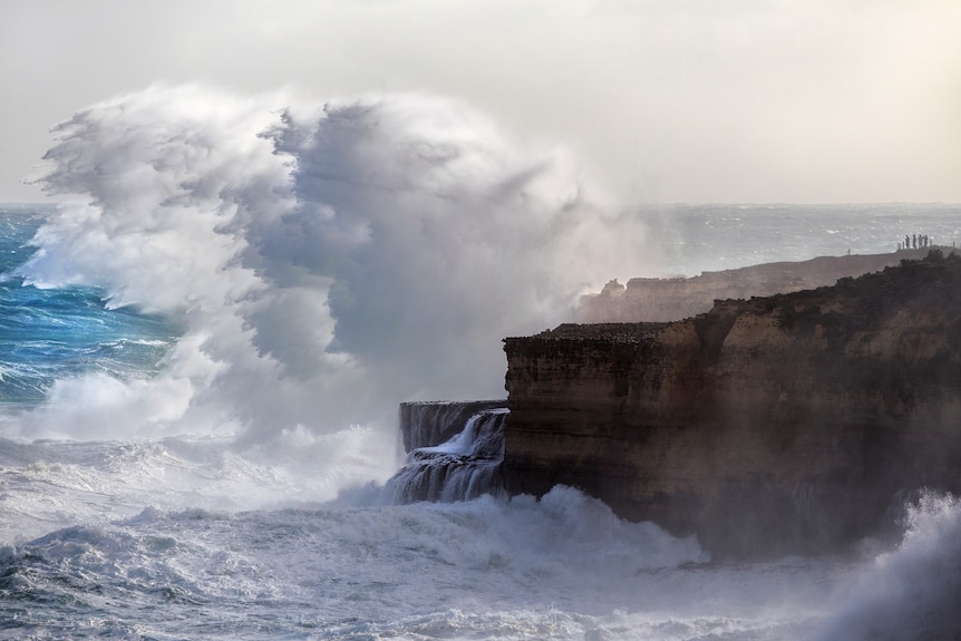 A large waves crashes into rock.