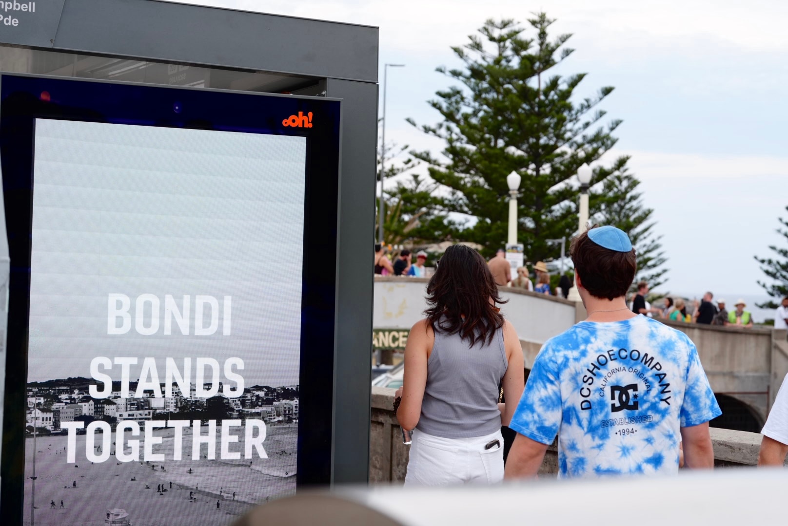 Duas pessoas passavam por uma placa eletrônica que dizia 