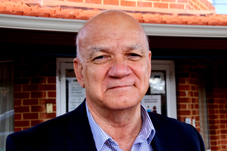 A close up head shot of Chris Hall standing in front of an aged care facility