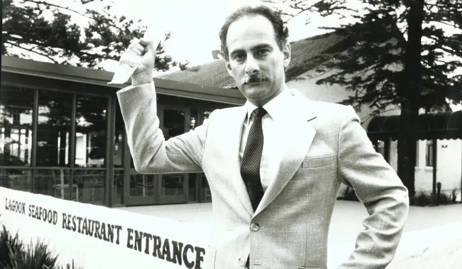 Una foto antigua de un hombre señalando un restaurante.