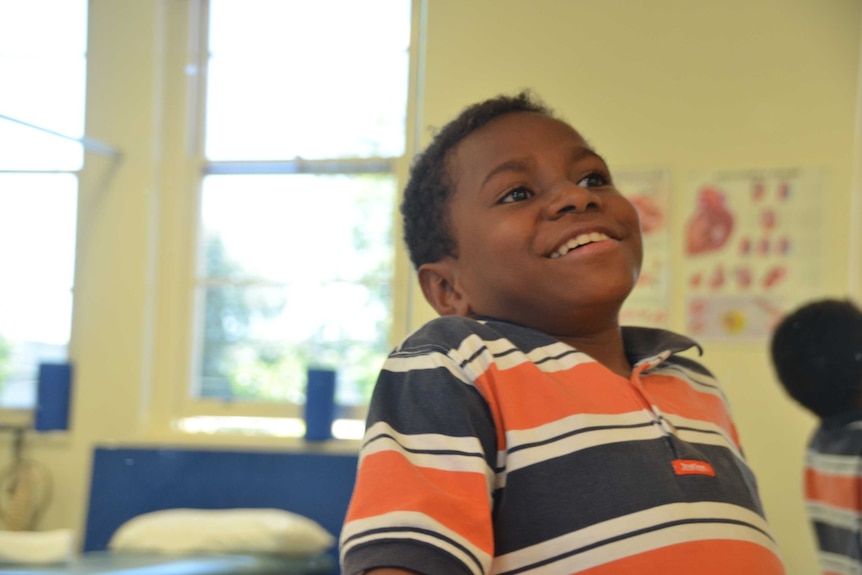 A mid shot of Edward, a boy from PNG, smiling, window in the back faded out.