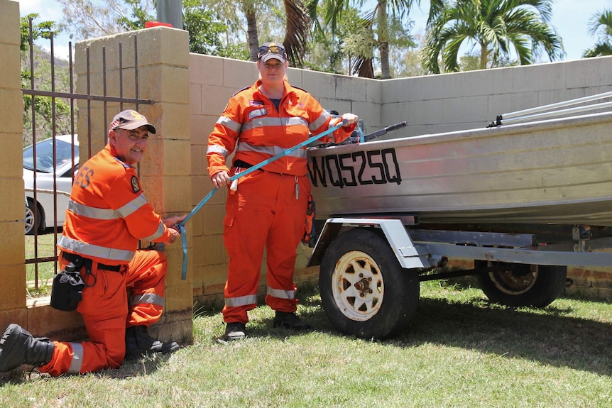 SES staff tie down a tinny boat in a back yard.
