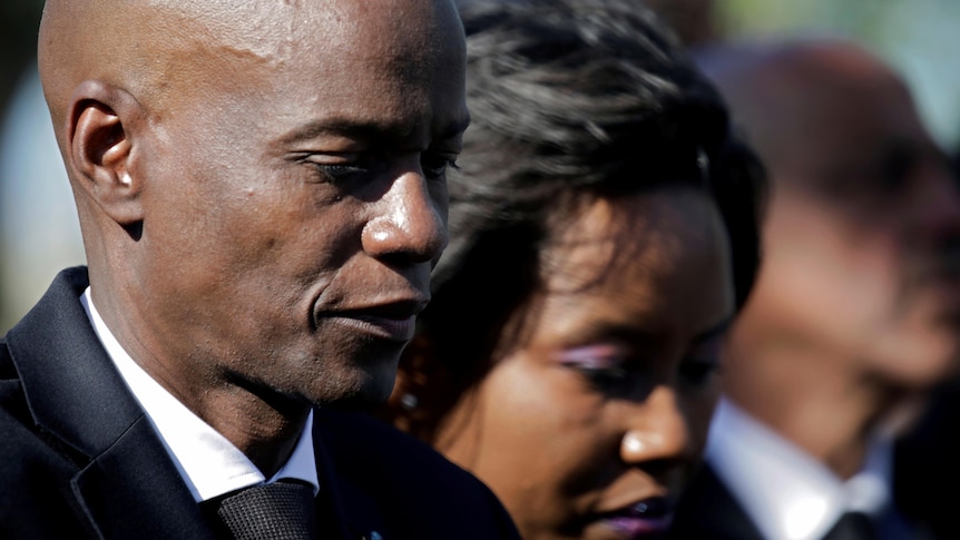 Jovenel Moise and his wife wearing black and looking down.