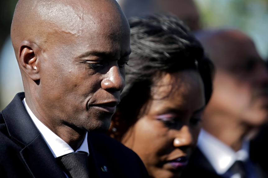 Jovenel Moise and his wife wearing black and looking down.