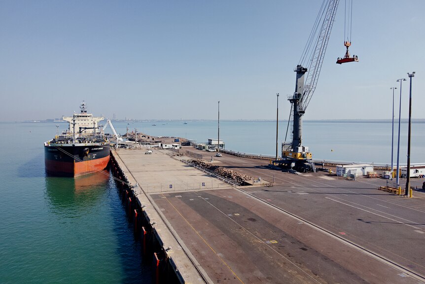 A ship anchored at a wharf part of the Darwin Port, on a sunny day.