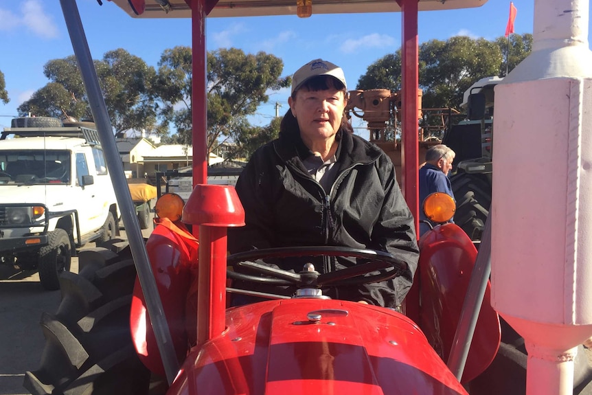 Carolyn Young sits on her red 35 Massey Ferguson tractor.