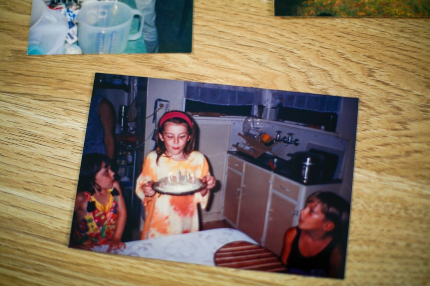 Polaroid of a young girl holding a birthday cake getting ready to blow out the candles.