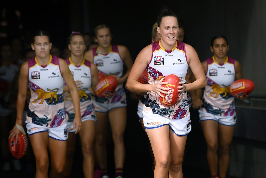 A smiling Emma Zielke leads the Brisbane Lions AFLW team onto Adelaide Oval