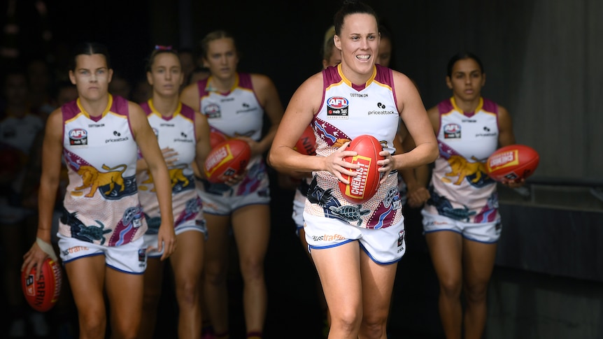 A smiling Emma Zielke leads the Brisbane Lions AFLW team onto Adelaide Oval