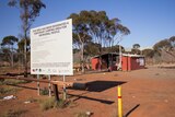 A sign in front of dusty area with a basic building says it is a temporary camping area for Aboriginal people.