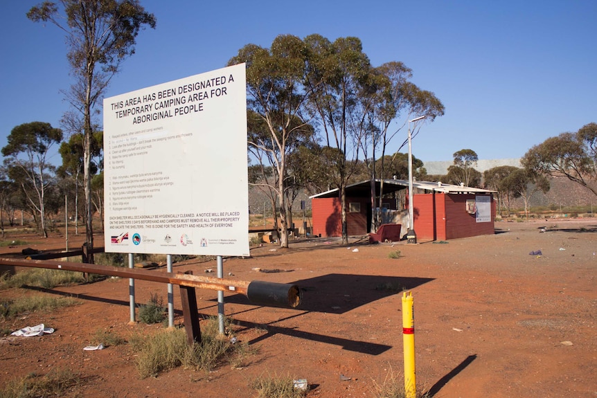 A sign in front of dusty area with a basic building says it is a temporary camping area for Aboriginal people.