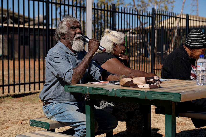 Eddie Robertson speaks into a microphone sitting at a table in Yuendumu.