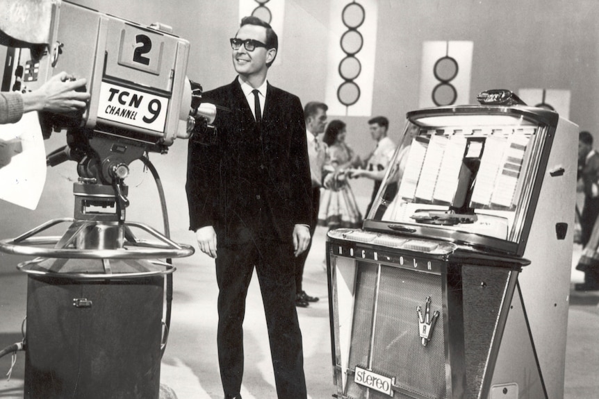 Brian Henderson stands in suit on set