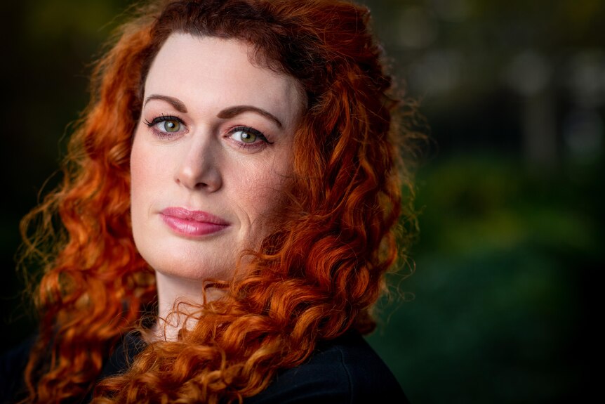 A woman with red curly hair and green eyes