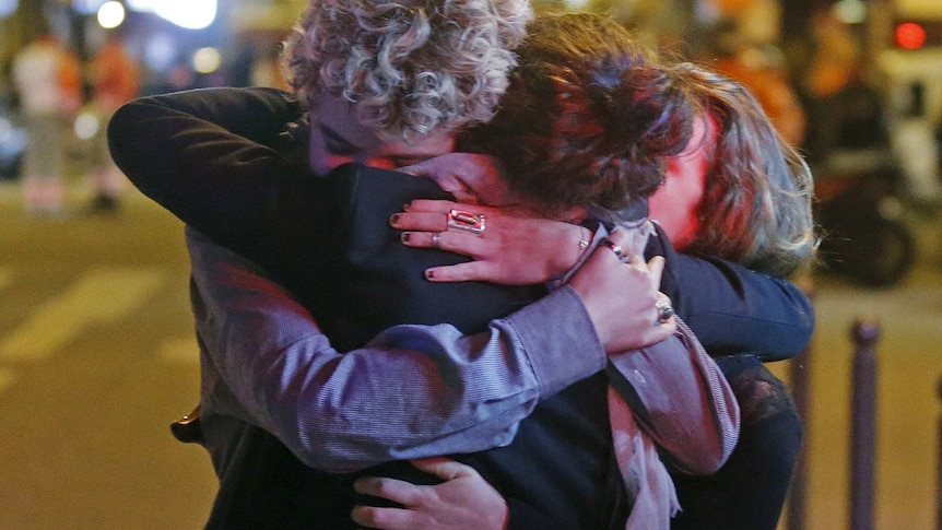 People hug on the street near the Bataclan concert hall