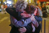 People hug on the street near the Bataclan concert hall