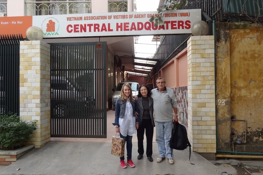 Man and two women,arm in arm, standing at entrance to a building with Central Headquarters sign above them.