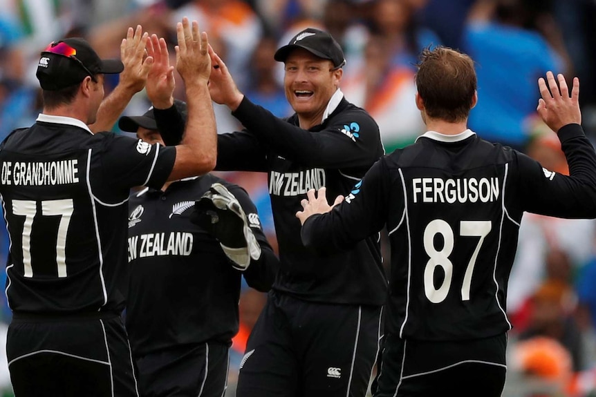 Cricketers dressed in black celebrate a wicket