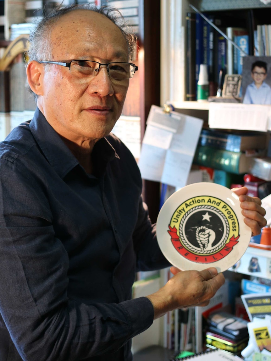 A man holds a plate labelled "Unity Action And Progress".