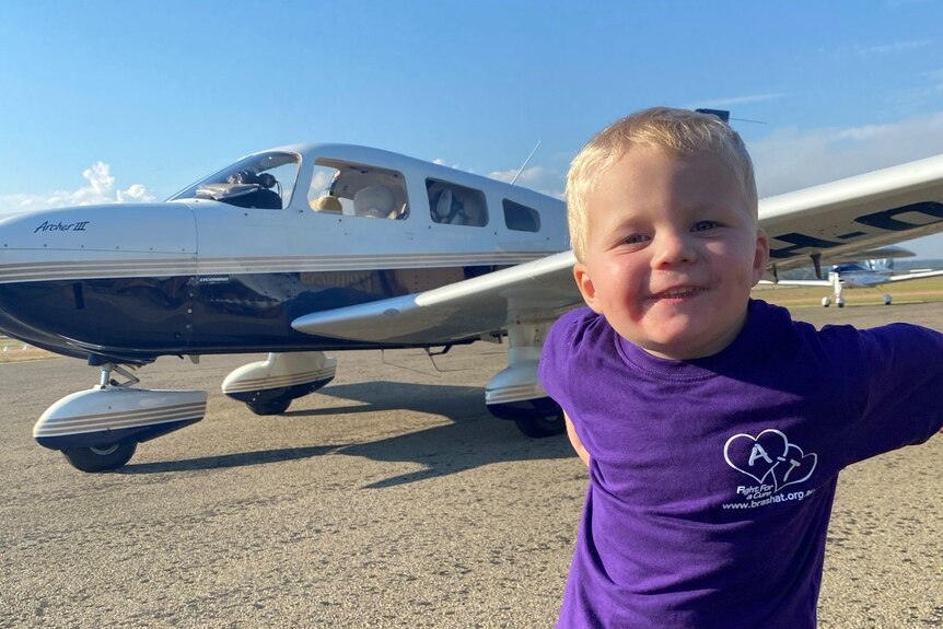 A 2-year-old boy standing in front of a plane