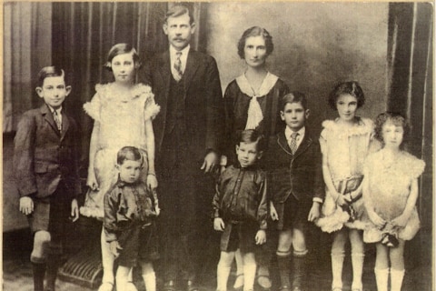 An old faded photograph of a husband and wife with seven children.