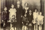 An old faded photograph of a husband and wife with seven children.