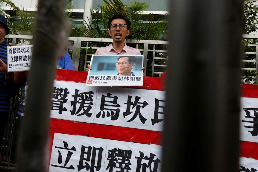 A protestor against the jailing of former Wukan village head Lin Zuluan holds a sign.