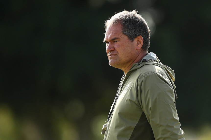 Rugby union coach standing, watching training 