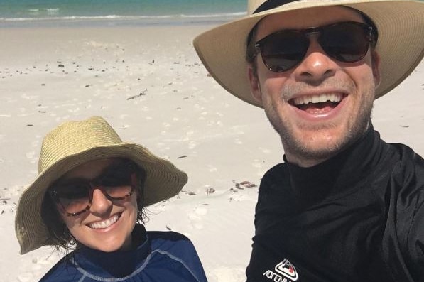 Zoe Foster Blake and Hamish Blake wear broadbrim hats and rash vests on while standing on beach in Queensland