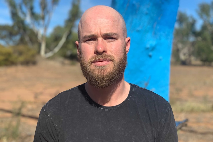 Portrait of Simon Comerford in front of a blue tree.